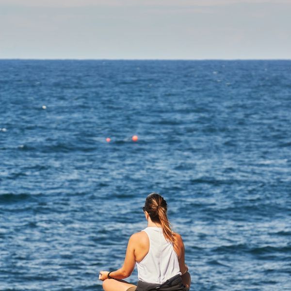 Woman sitting in a serene lotus position, meditating outdoors.